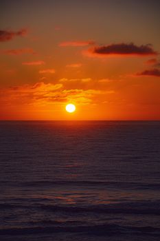 A captivating sunset over the ocean with vibrant orange hues and calm waves.