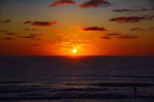 Free A stunning sunset over the ocean, featuring vivid colors and tranquil waves. Stock Photo