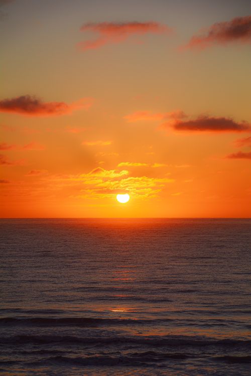 Free Breathtaking sunset over the ocean with vivid orange hues and a serene seascape. Stock Photo