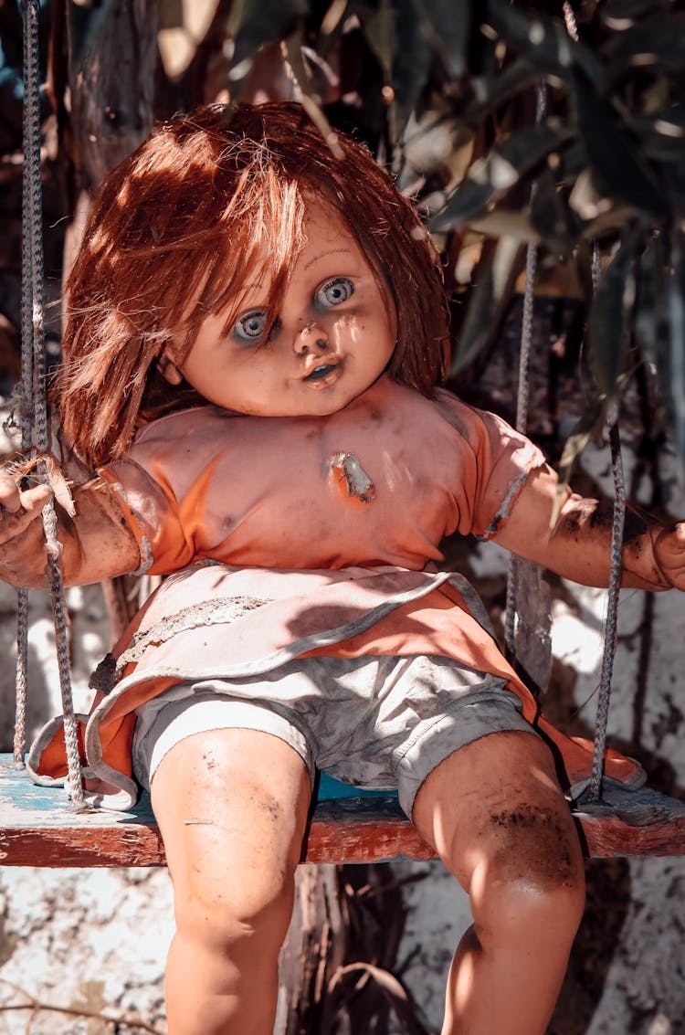 Plastic Doll Sitting On A Swing