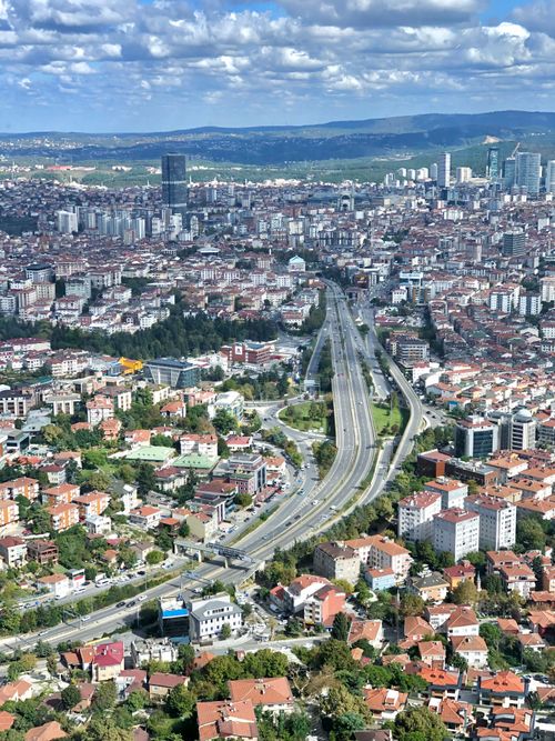 Free Expansive aerial view of a bustling cityscape with a central highway, skyscrapers, and residential areas under a clear blue sky. Stock Photo