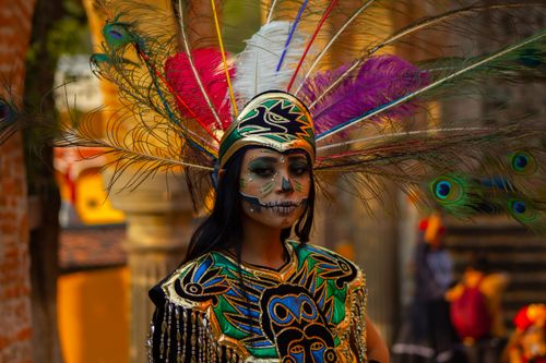 Free Woman in traditional costume with creative makeup and feathered headdress, outdoors. Stock Photo