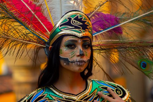 Free Colorful portrait of a woman with Catrina makeup and an elaborate feather headdress, embracing cultural heritage. Stock Photo