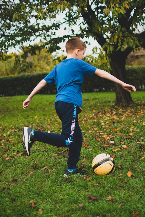A Boy in Blue Shirt Playing Football