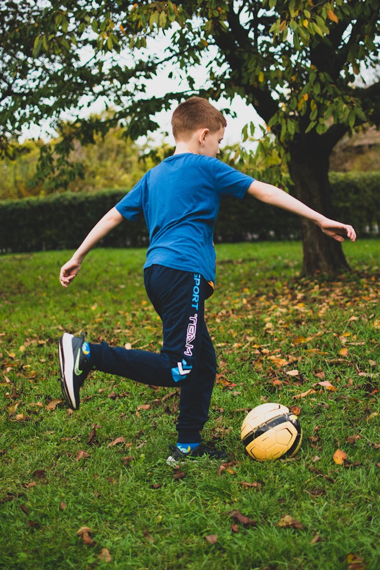 A Boy In Blue Shirt Playing Football