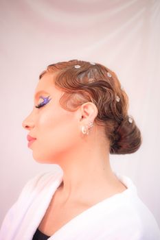 Artistic side profile of a woman with vintage hairstyle and vibrant makeup.