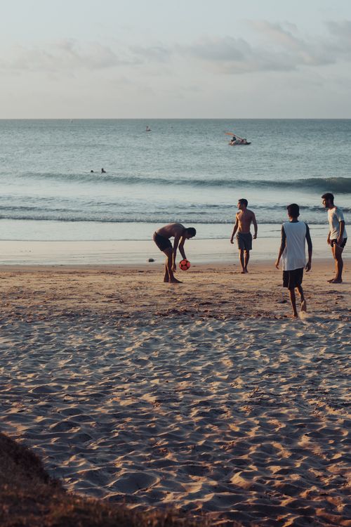 Free Group of young adults enjoying a game of soccer at Paracuru Beach, Brazil during sunset. Stock Photo
