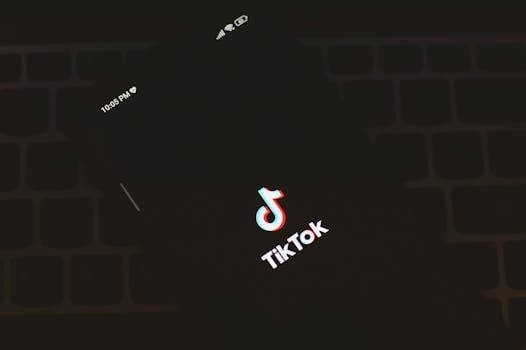 Close-up of a smartphone displaying the TikTok app logo against a dark keyboard background.