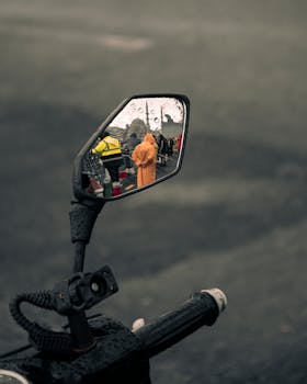 Motorcycle side mirror reflecting street scene on a rainy day in Istanbul.