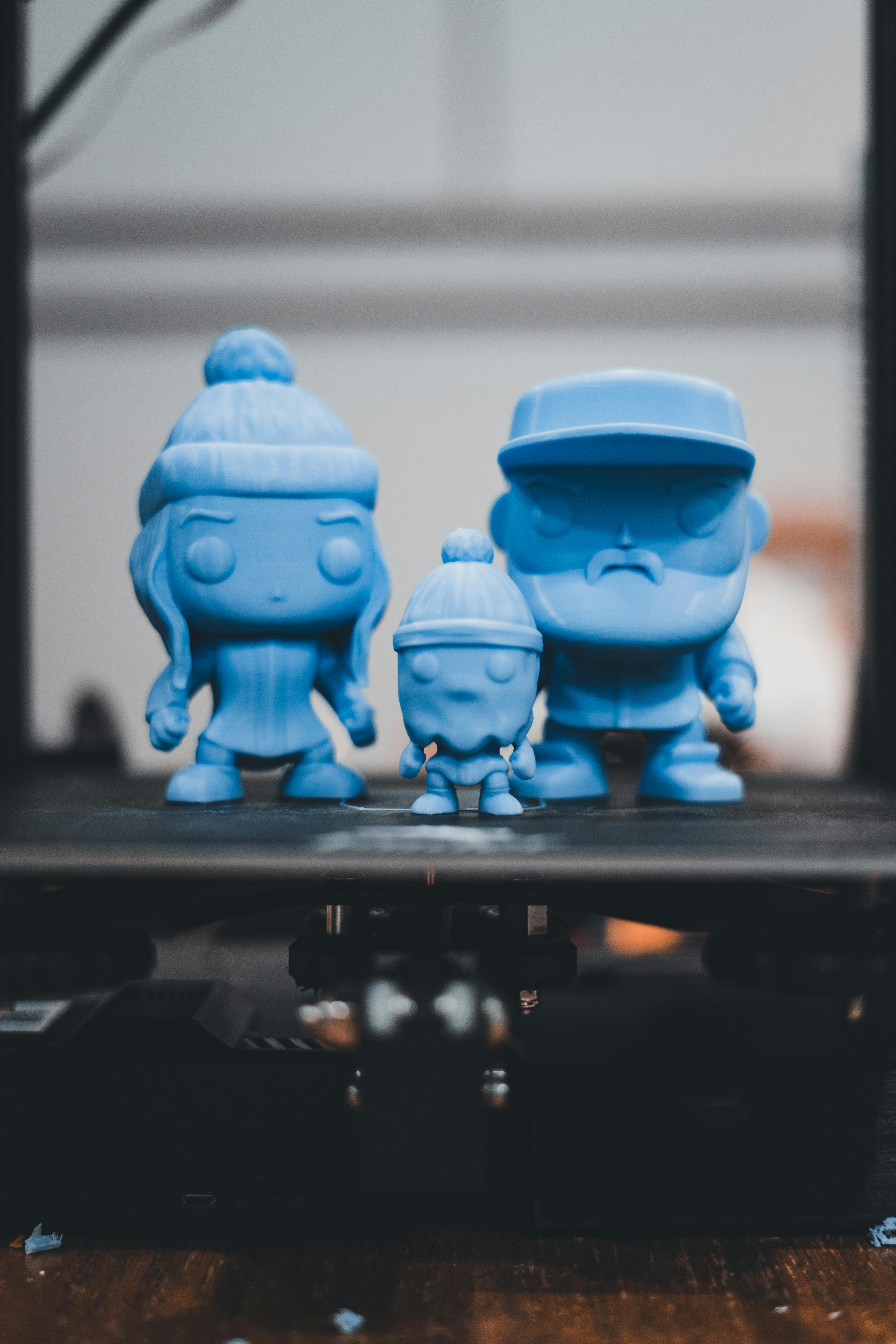Close-up of blue 3D printed figurines on a printer bed, showcasing modern craftsmanship.