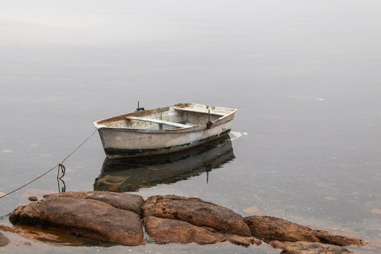 A Boat On Water Near The Rock