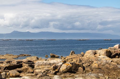 Free Rugged rocky coast with a clear blue sea and distant mountains in Meloxo, Spain. Stock Photo