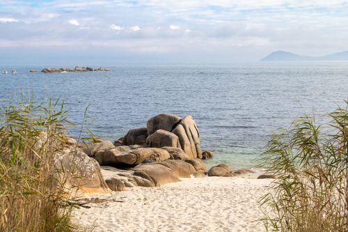 Free Scenic view of a rocky beach in El Grove, Spain, with ocean waves and clear skies. Stock Photo