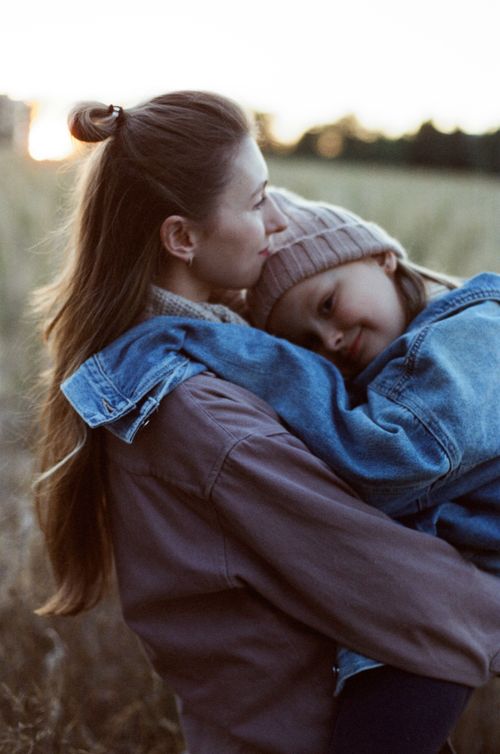 Free A heartwarming outdoor portrait of a mother lovingly holding her daughter during a peaceful day. Stock Photo