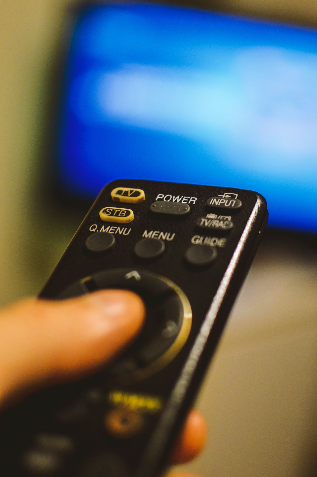 テレビのリモコンを持つ手（視聴判断のイメージ）