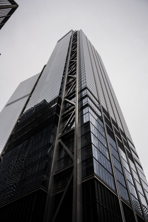 Free Dramatic low angle shot of a modern skyscraper with steel and glass facade under a cloudy sky. Stock Photo