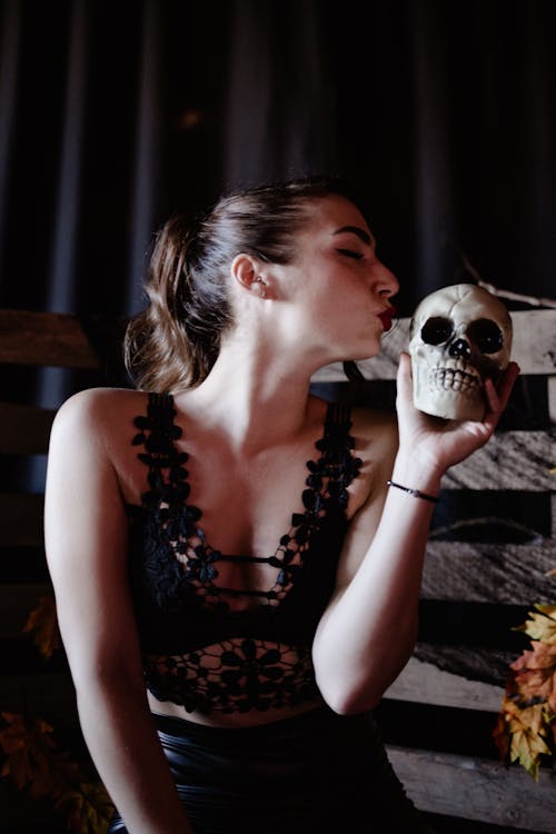 Close-Up Shot of a Woman in Black Lingerie Holding a Skull