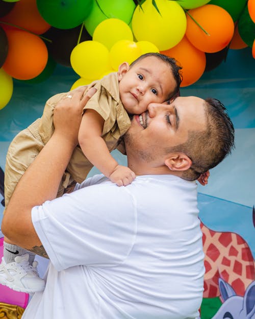 Free A Man in White Shirt Carrying His Son Stock Photo