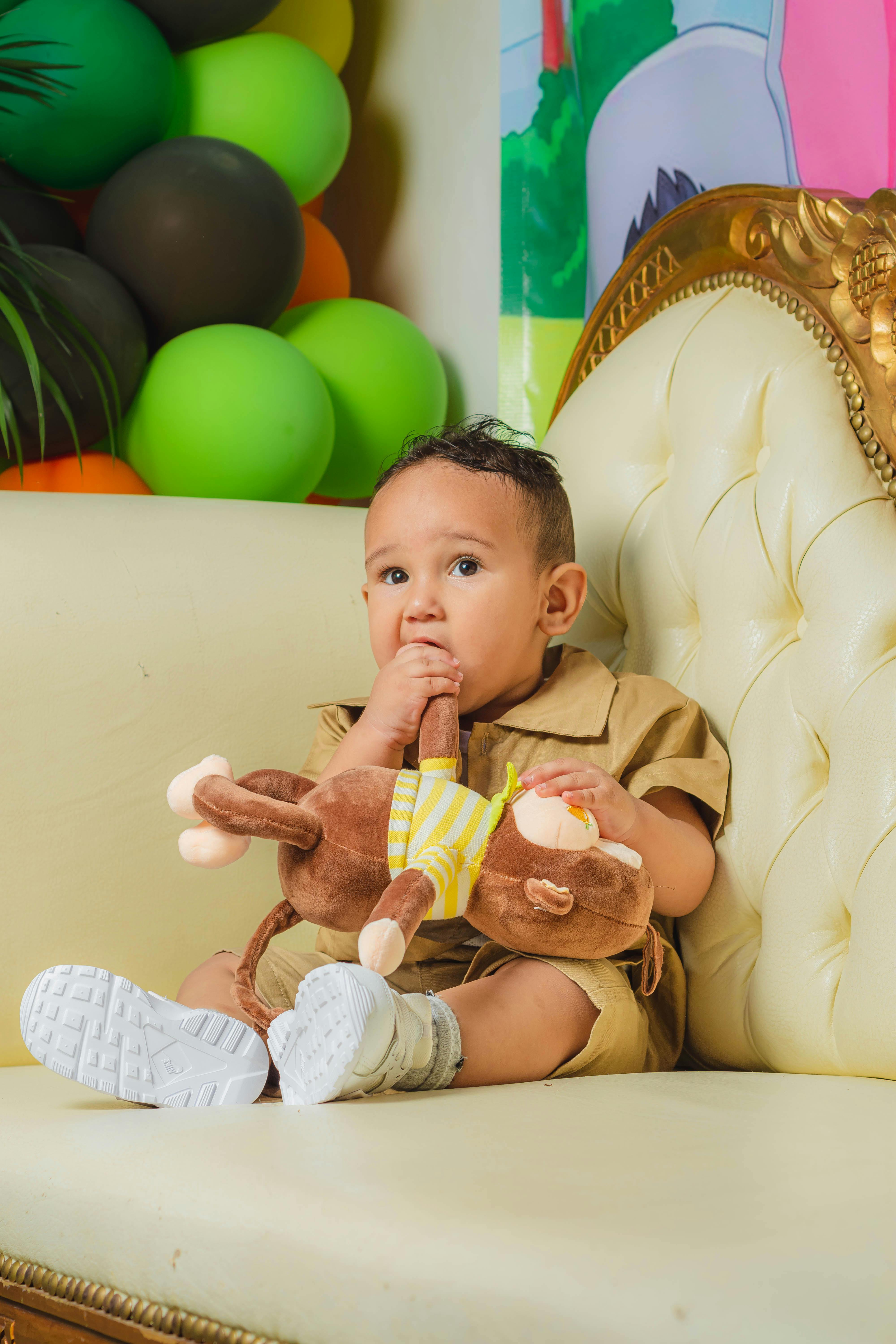 baby with a stuffed toy sitting on a chair