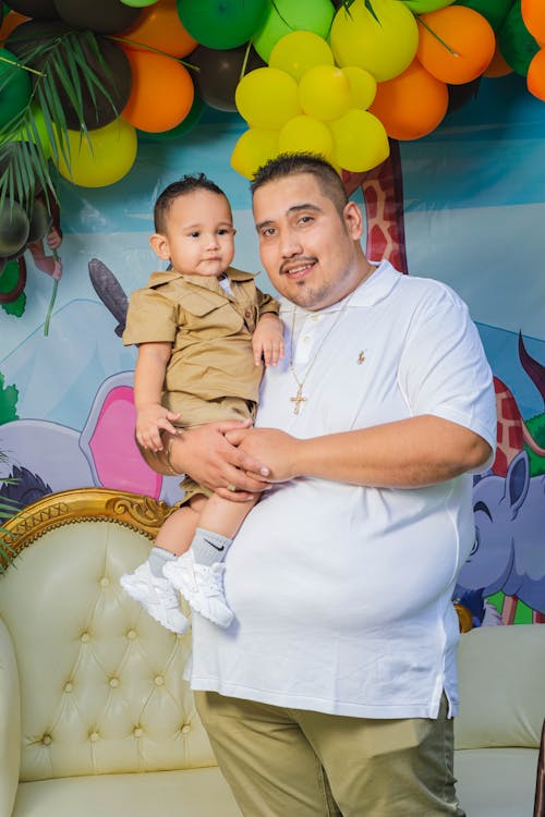 A Man in White Polo Shirt Carrying a Baby Boy