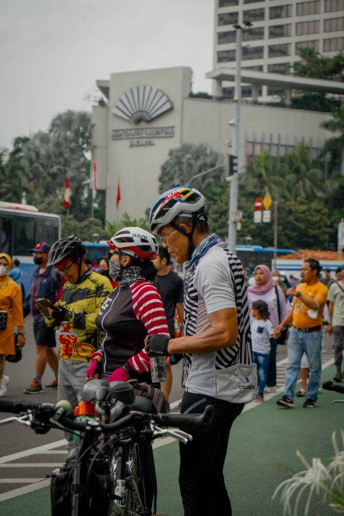 Free Cyclists and pedestrians interact near Mandarin Oriental Jakarta on a lively street. Stock Photo