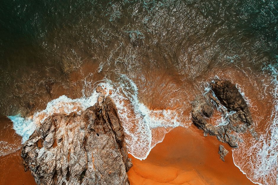 Stunning aerial view of ocean waves crashing on rocky coast, showcasing nature's beauty.