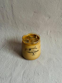 Delicious iced coffee in a rustic glass mug on a textured surface, perfect for a refreshing break.