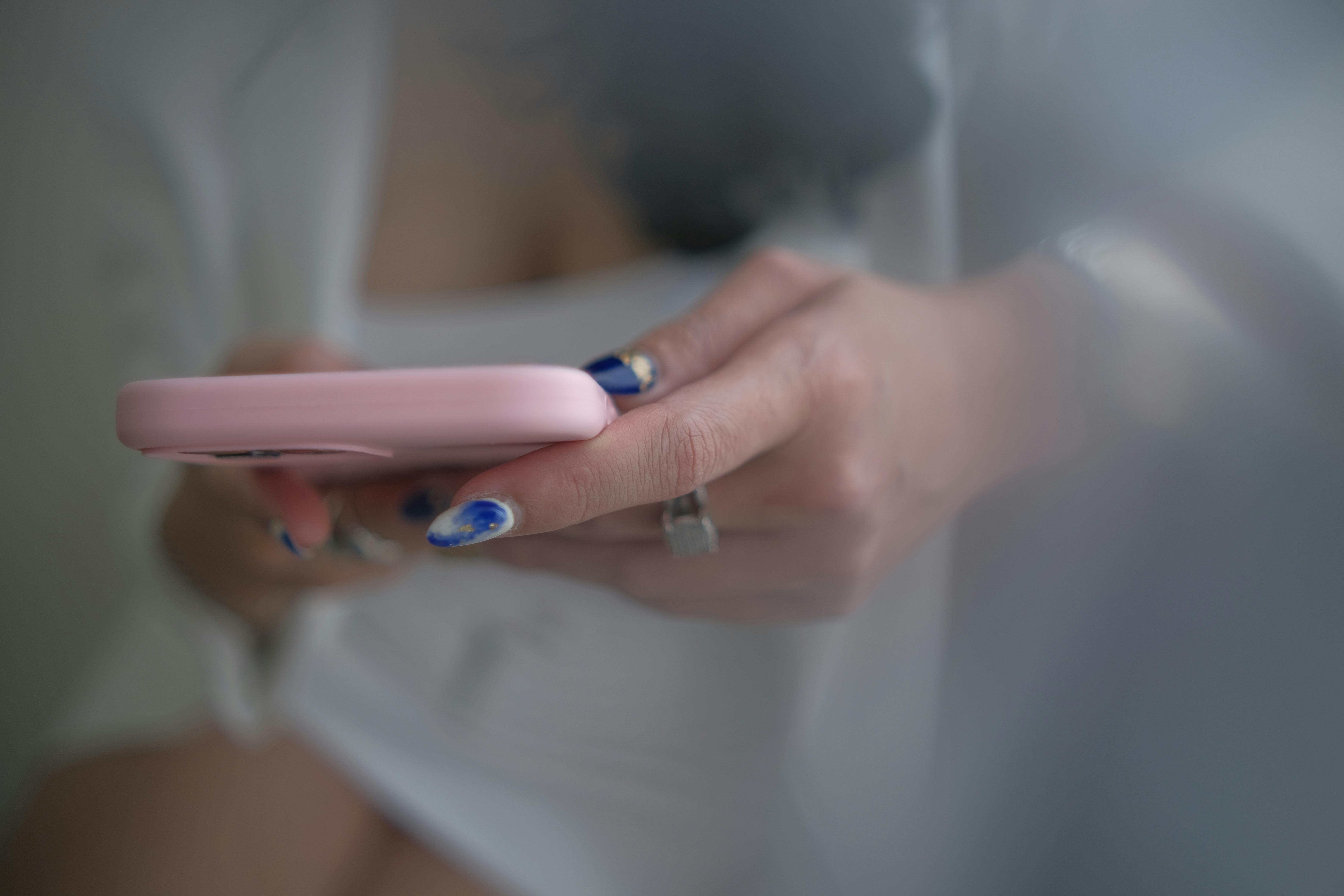 a close up shot of a woman with manicured nails using her smartphone