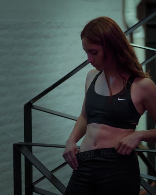 Free Portrait of a fit woman in sportswear at a gym, showcasing her toned physique. Stock Photo