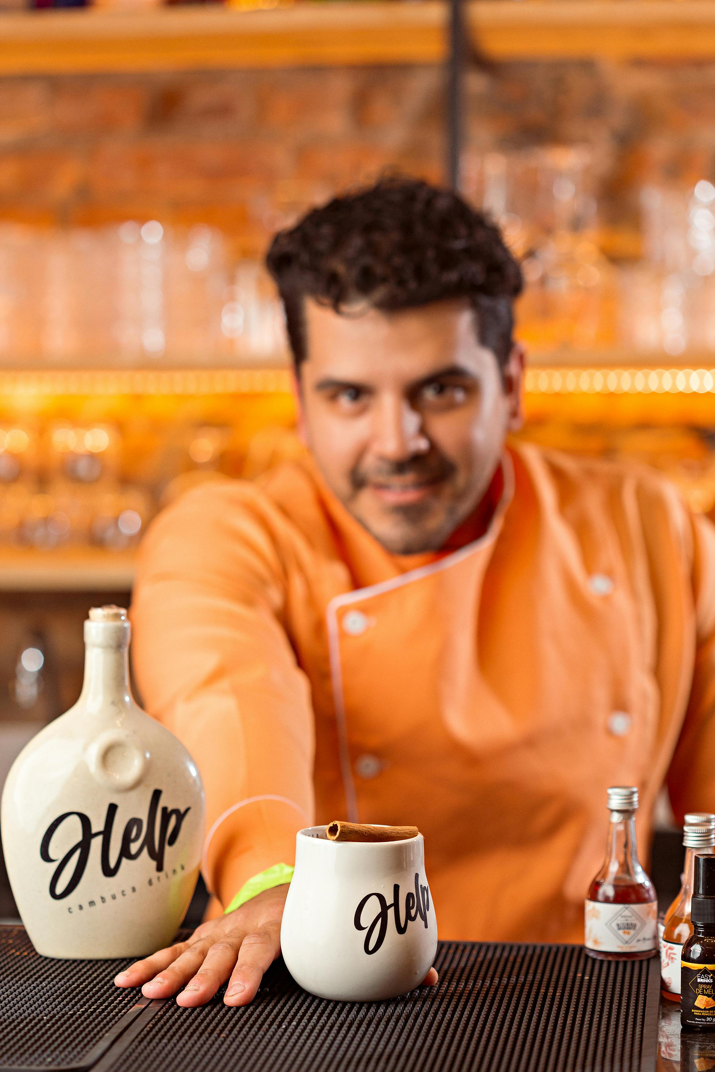 Cheerful bartender in orange offering a drink in a cozy bar. Vibrant and inviting atmosphere.