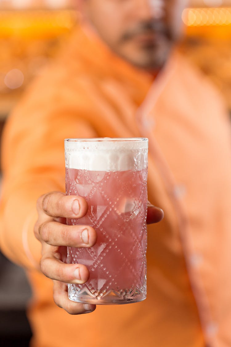 A Person Holding A Glass Of Cocktail