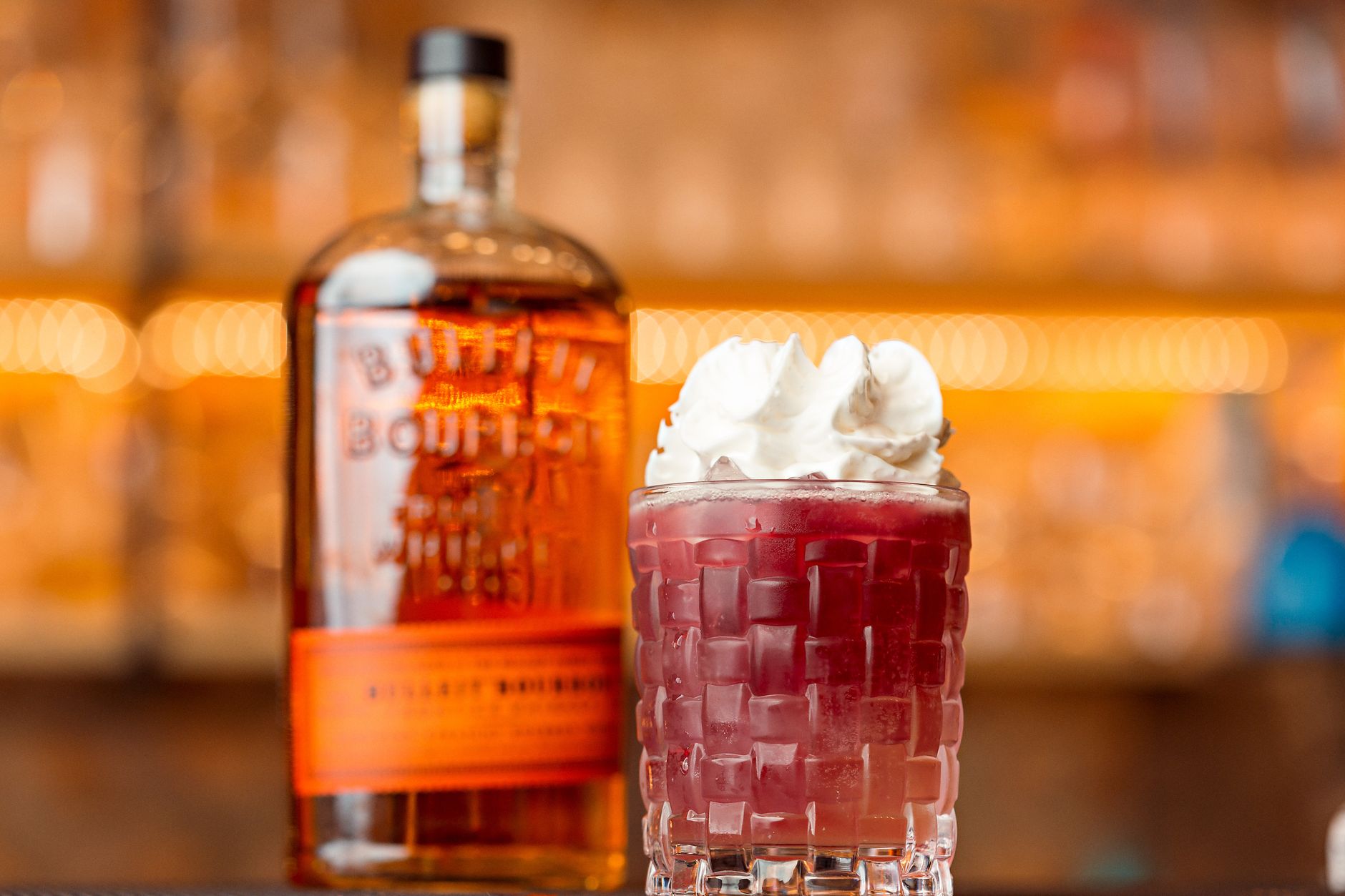 Bottle of Four Roses bourbon on a wooden surface with glowing amber liquid