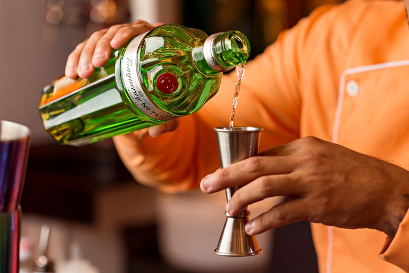 Close-up of a bartender pouring gin into a jigger, preparing a cocktail