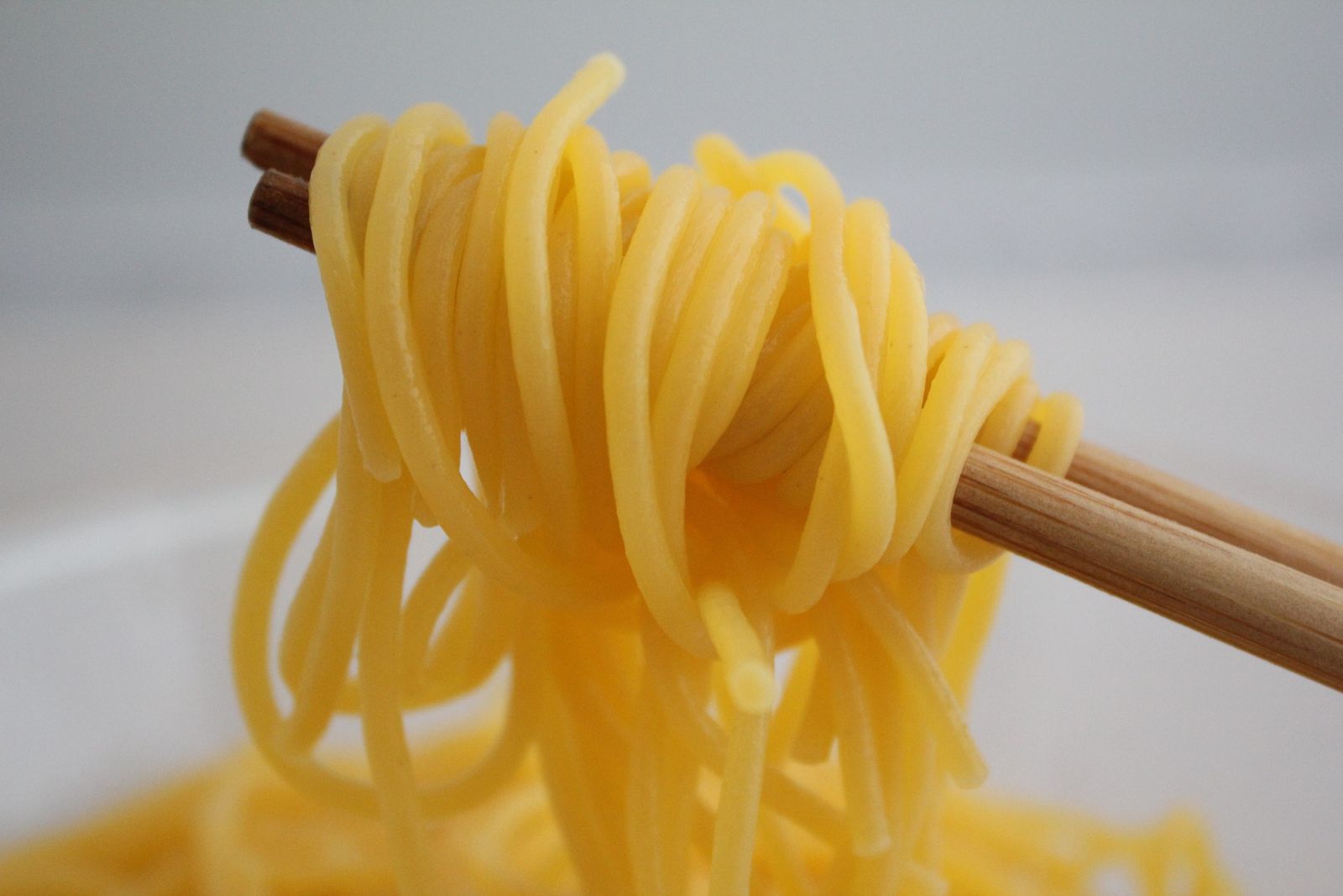 Asian pasta dishes noodles lifted with chopsticks close-up detail