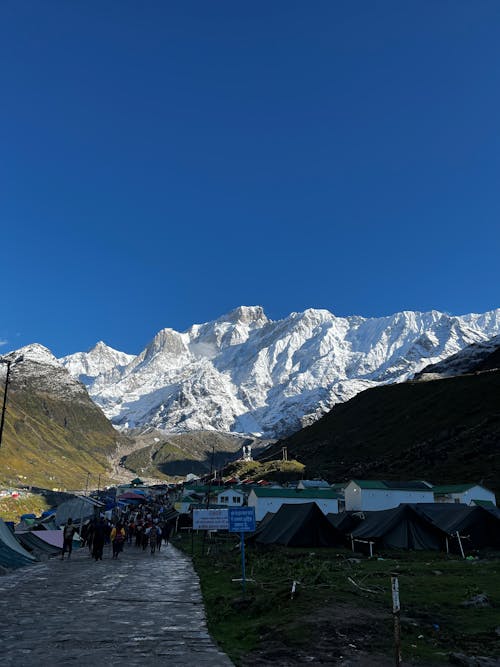 People Walking through Village in Mountain Valley in Blue Sky