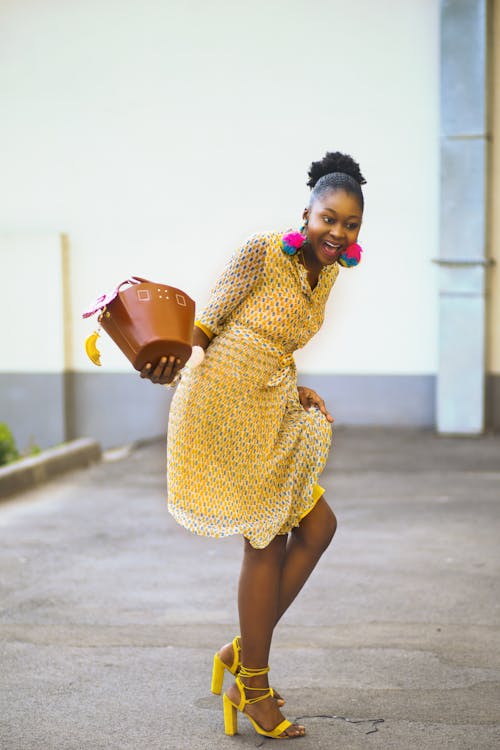 Mulher De Vestido Rosa Segurando Uma Bolsa Marrom Em Pé