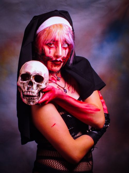 Free A woman in creative cosplay makeup holding a skull, perfect for Halloween or gothic themes. Stock Photo