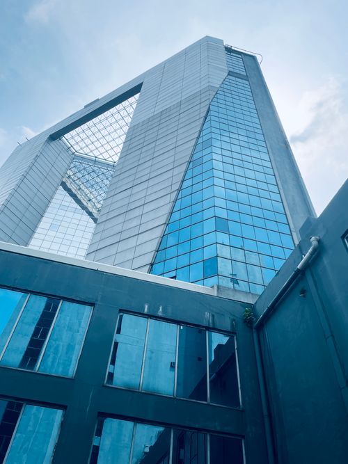 Free Low-angle shot of a modern skyscraper with a reflective glass facade against a blue sky in Kolkata, India. Stock Photo
