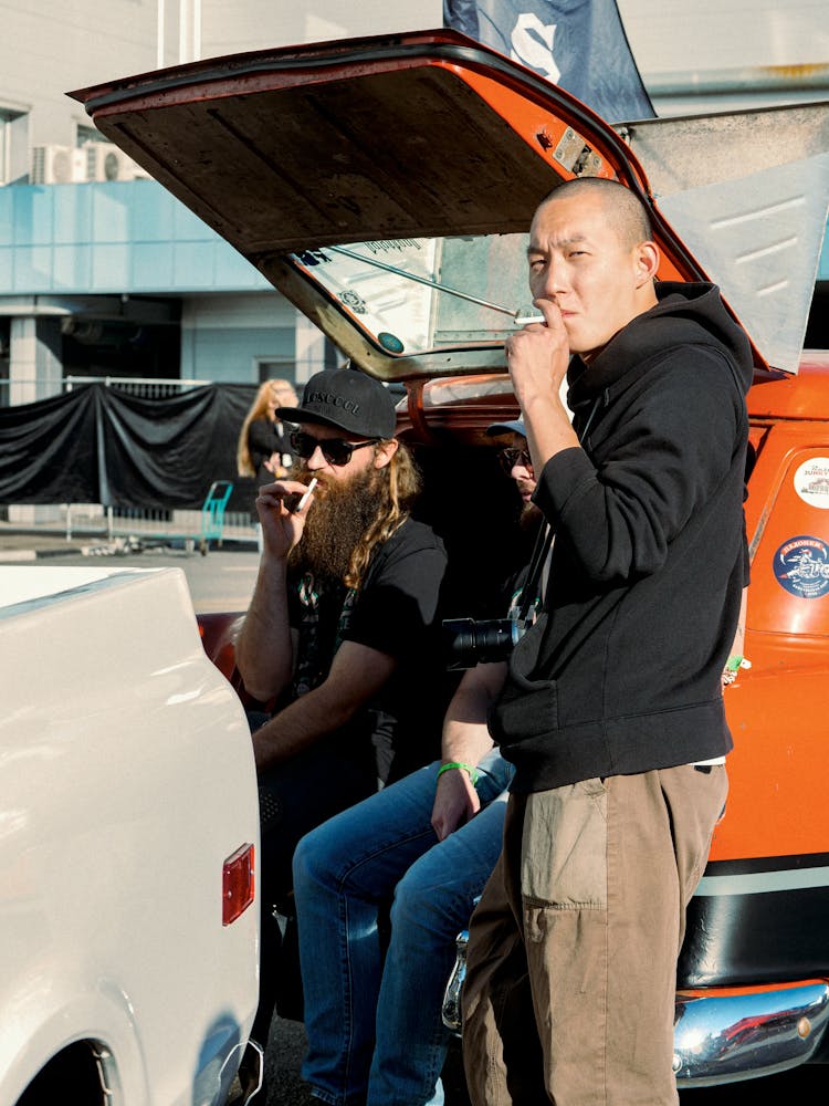 Men Standing Between Cars And Smoking Cigarettes 