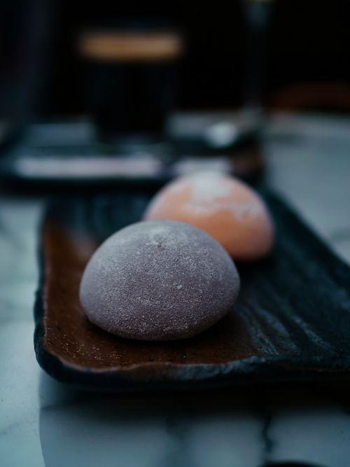 Free Close-up of two mochi in soft light with a coffee backdrop, emphasizing texture. Stock Photo