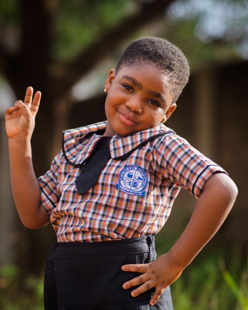 Free Charming young girl in school uniform confidently posing outdoors, expressing joy and pride. Stock Photo