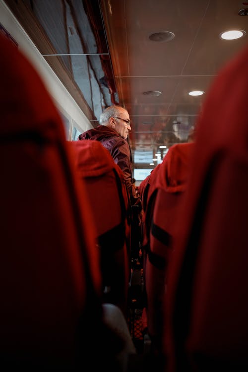 An Elderly Man Standing Near the Seats of Public Vehicle