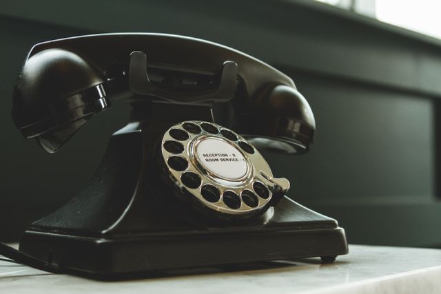 Classic black rotary phone on hotel reception desk, evoking nostalgia and vintage charm. Related image for AI in Hospitality: The Practical Guide for Hotel Teams.