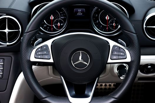 Detailed view of a Mercedes steering wheel and dashboard showcasing modern car interior design.