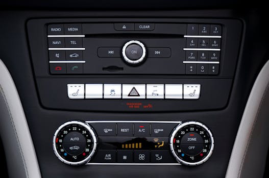 Close-up of a car's dashboard showing AC and media controls, dials, and electronic switches.