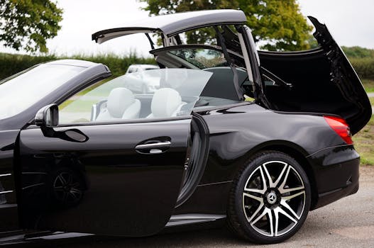 Side view of a sleek black Mercedes convertible car with doors and roof open, showcasing luxurious design.