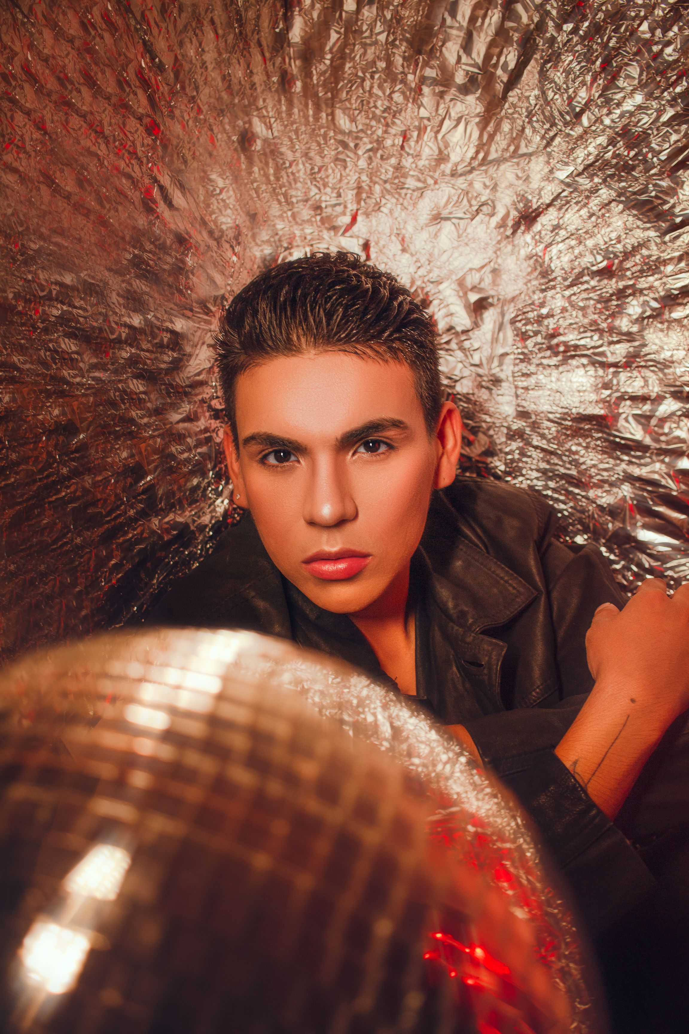 Portrait of a young man with a disco vibe set against a shimmering backdrop, Goiânia, Brazil.