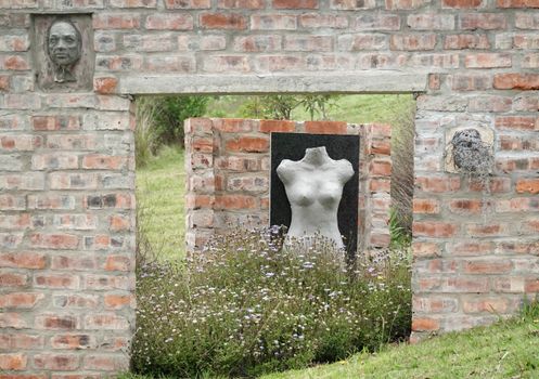 Brick wall with sculptures in an outdoor garden setting, surrounded by flowers.