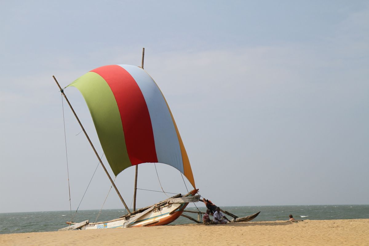 A vibrant fishing boat with colorful sails docked on Negombo Beach, Sri Lanka.