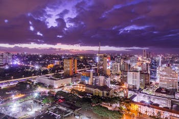 Illuminated Cityscape and Purple Sky with Clouds